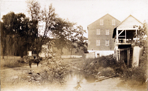 Image of Folck's Mill; 2 barns and horse standing on the road