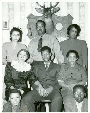 Family of 8 pose for portrait with a mounted dear head on the back wall
