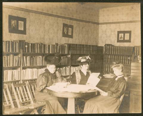 3 women seated at round table in Boonsboro Library reading books;1907