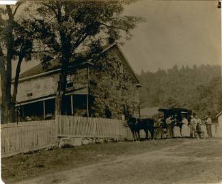 Book wagon with horse parked outside of home with fence