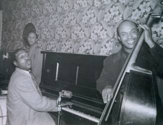 Man playing piano with microphone stand near; man hold bass cello 