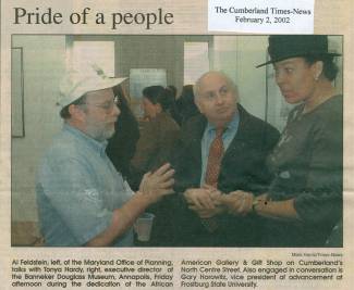 2 men talking to woman in hat; people in background talking