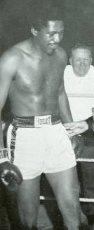 Photo of boxer preparing to fight in ring with trainer in background