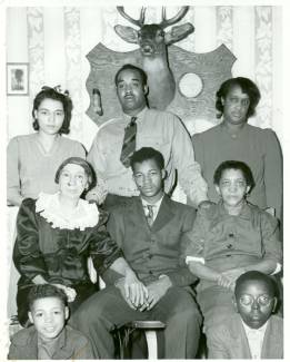 Family of 8 pose for portrait with a mounted dear head on the back wall