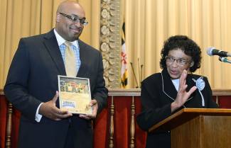 Image of man holding a plaque and woman behind podium speaking