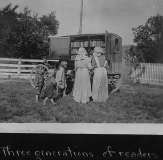 Bookwagon on country road; family surrounds, looking through books