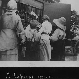 Book wagon on country road; women and children looking on bookshelf for books