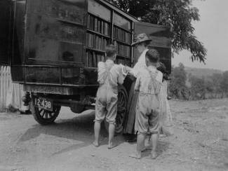 Book wagon on country road; women and children looking through books