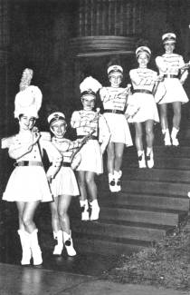 6 Drum Majors standing on individual stairs holding batons 