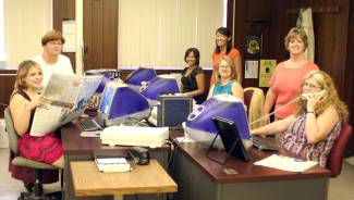 Women in office with computers gather for photo, Cumberland Times-News editorial staff