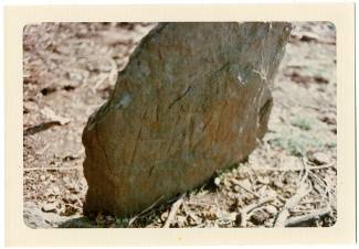 Large rock, this gravestone has "M.W." scraped into it