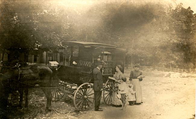 Book wagon with horse 3 people standing in front of a house