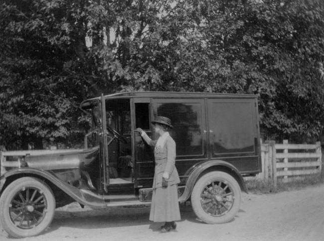 Bookwagon parked on country road; woman standing outside of wagon