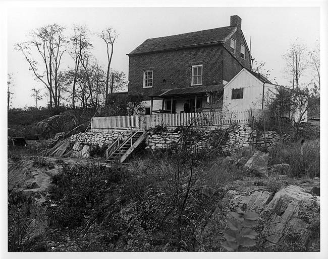 Lockhouse, Guard Lock 5; house sets up on top of a hill with fence and brick wall