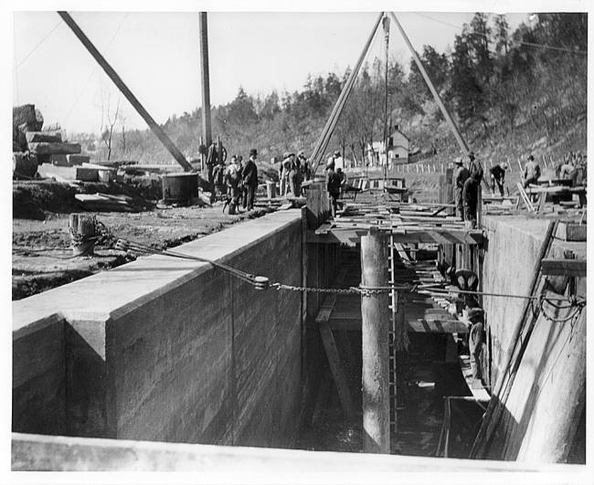 Lock 33 reconstruction, concrete wall on both sides with scaffolding in middle and workers throughout