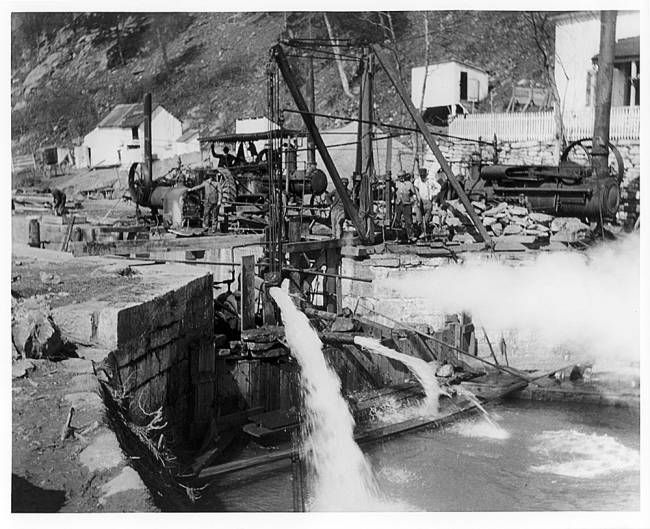 Lock 33 reconstruction, water spewing out while workers seen on machine controlling water flow, circa 1930s