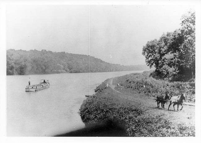 Canal boat in river; 2 horses on road near river, circa 1920