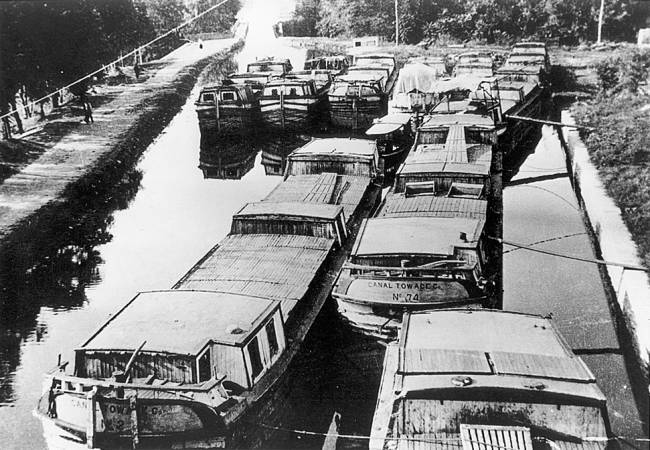 Collection of more than 10+ boats tied up in canal at Williamsport; circa unknown