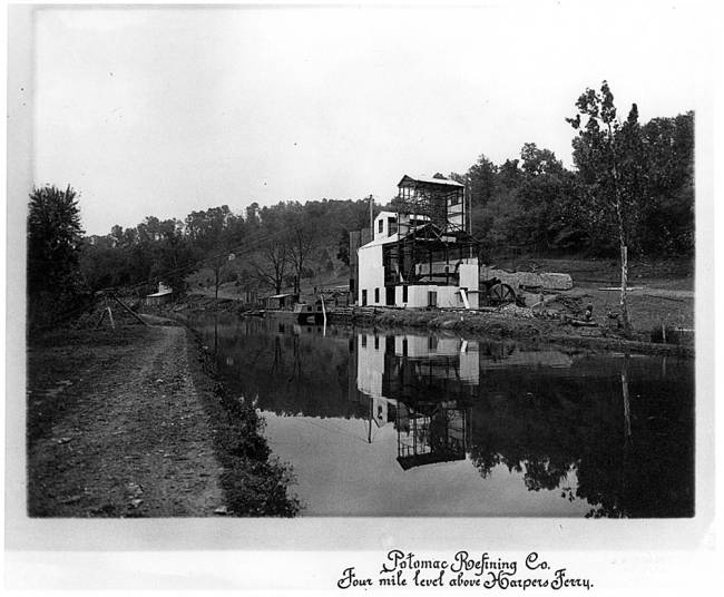 2 story Building along canal with canal boat outside; text reads "Potomac Refining Co. Four mile level above Harpers Ferry"