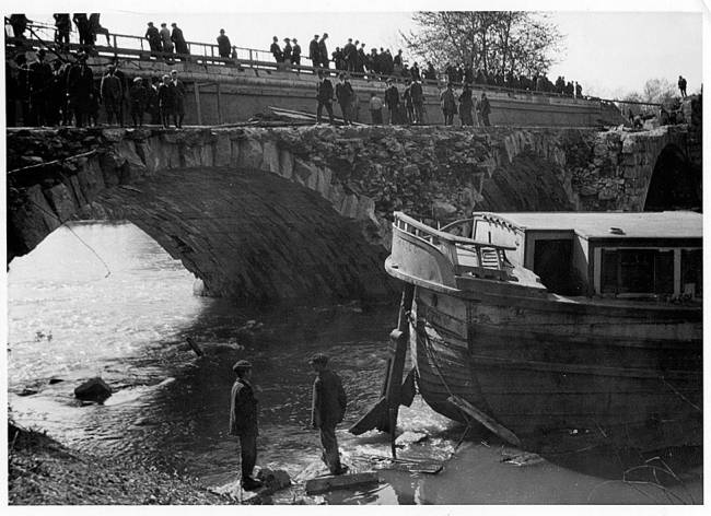 berm side of the Conococheague Aqueduct collapsed into the Conococheague Creek; canal boat with several people standing on bridge and 2 men in water near boat