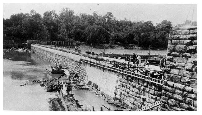 Repairs on Dam 4; workers are seen on the dam making repairs