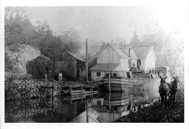 Docked boat with 2 mules at Pinesburg. Several people seen standing on boat; circa 1895