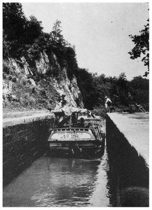 Boat in canal, coming through workers are on both sides of canal