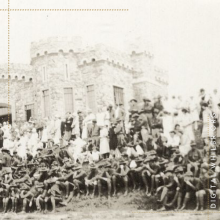 A crowd sits outside Headquarters, also known as the Castle Building.