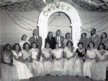 Photo of 1950-1951 Carver High School Junior-Senior Prom; girls seated in front in formal dress, administrators standing in back