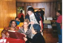 3 women seated and one standing looking through MLK display at Fulton Myers Post 2004