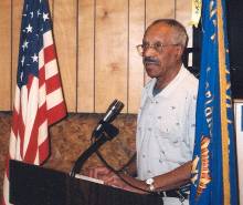 William Colbert speaking at the Fulton Myers Post #153; American flag and Post flag on both sides