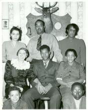 Family of 8 pose for portrait with a mounted dear head on the back wall