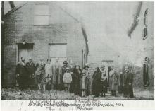 Photograph of multiple African Americans standing in front of a building