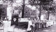 Klu Klux Klan parade; members with white robes, hoods and banners circa 1925