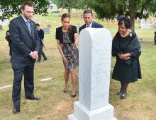 4 people in cemetery look over the newly restored grave marker for Jacob F. Wheaton