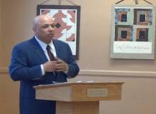 Man speaking at podium with artwork on the walls