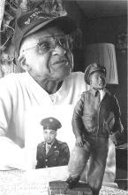 Photo of Clifton Brooks with portrait of military photo and miniature Tuskegee airman model statue