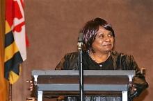 Women speaking at a podium with a Maryland flag in the back