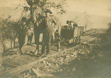 Coal car being pulled by man with mule