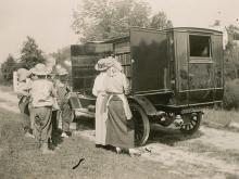 Book wagon on country road; women and older children looking through books