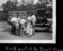 Book wagon's first visit in country; family of 6 standing beside wagon looking through books