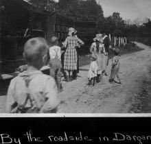 Bookwagon visits a family along side of road; children and women standing outside looking through books