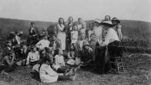 Group of children sitting in countryside listening to librarian read a story