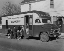1960's Bookmobile with children lined outside waiting to look through books inside
