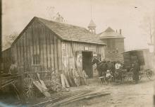 Photograph of blacksmith's barn with horse and book wagon at barn door