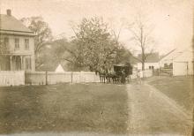 Book wagon with horse standing in front of a house