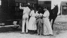 Book wagon on country road; family looking through books while a horse looks too