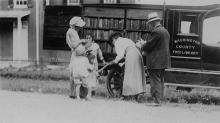 Book wagon on country road; women and children looking through books