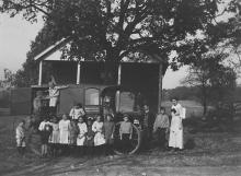 Bookwagon outside country home with several children posing for picture