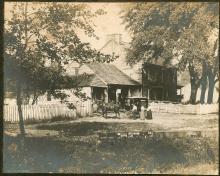 Book wagon with horse people standing in front of a house with white picket fence